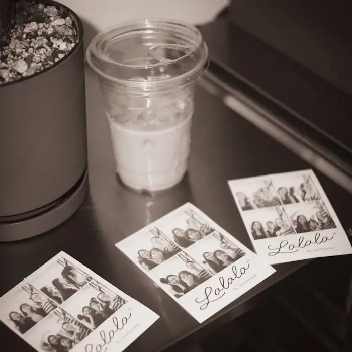 Printed photo booth strips resting on a table beside a drink